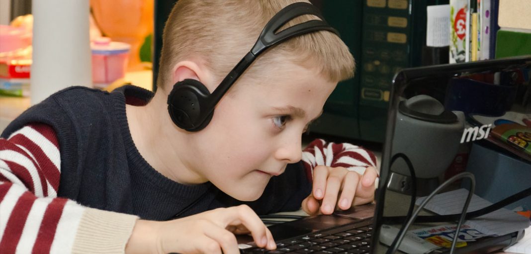 Boy-playing-video-games-on-laptop-computer-by-Chris-Parfitt